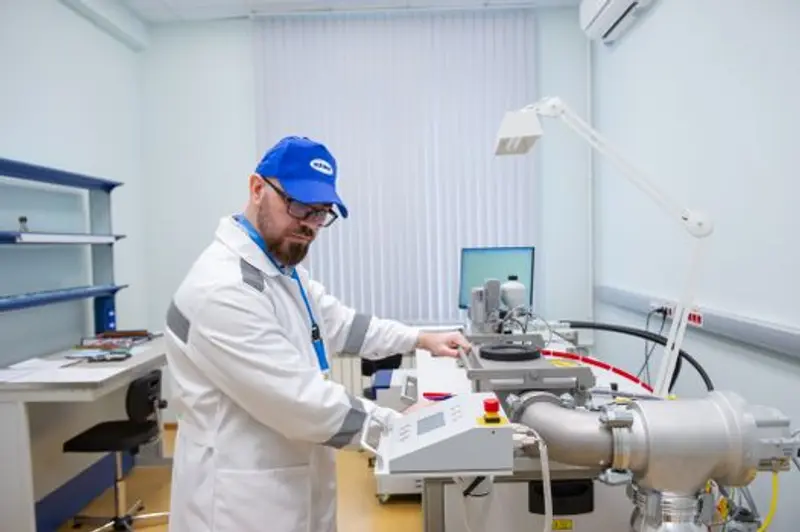 Teknisi laboratorium berjas putih mengoperasikan peralatan ilmiah canggih di dalam ruangan