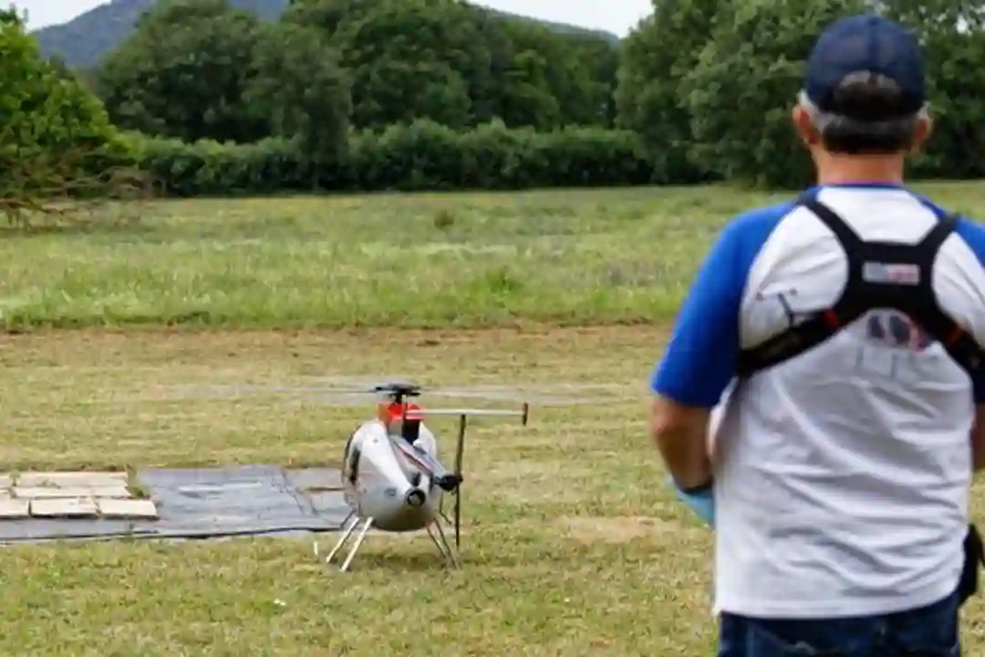 Pria mengendalikan helikopter remote control di lapangan berumput.