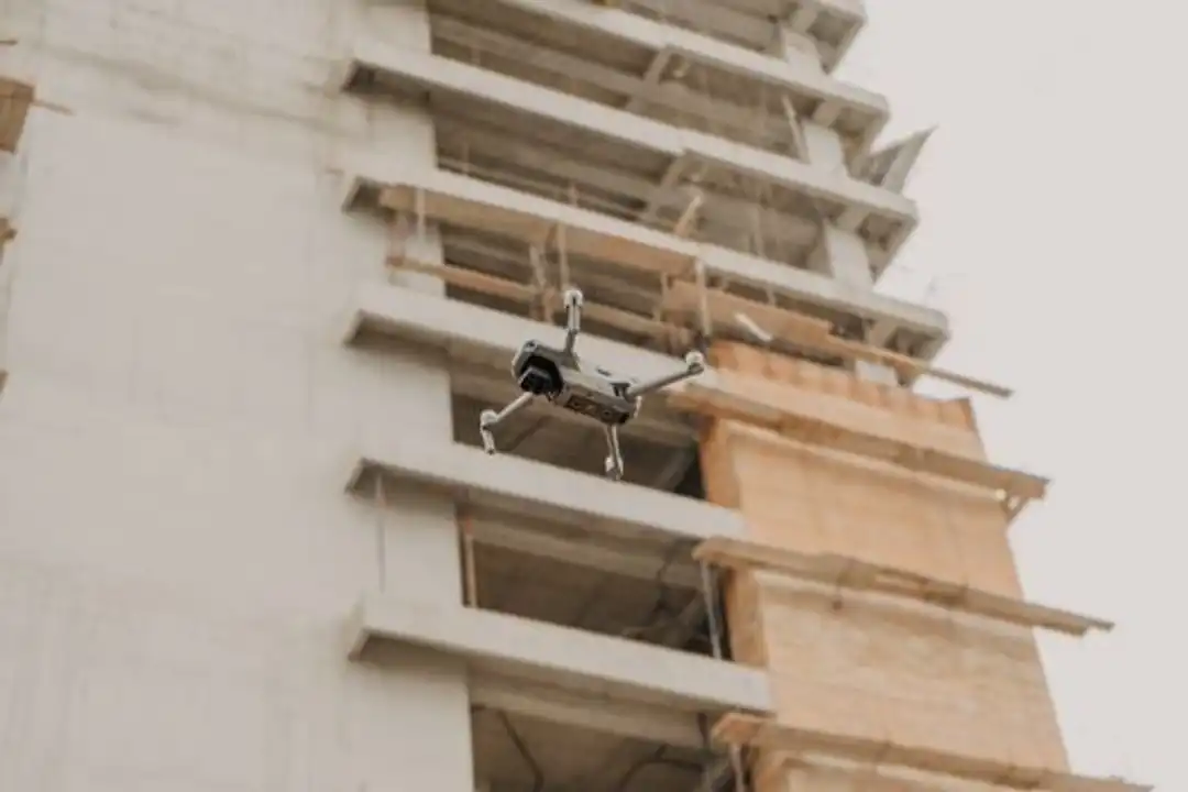 Drone terbang di dekat lokasi konstruksi di perkotaan Guatemala, relevan untuk pelatihan drone konstruksi.