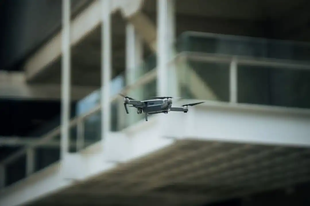 Drone canggih melayang di dalam lingkungan arsitektur, menyoroti teknologi terkini untuk pelatihan drone konstruksi.