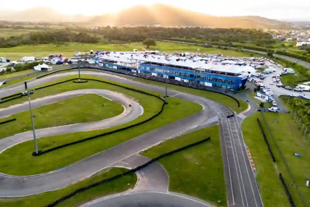 Foto udara lintasan go-kart dikelilingi lanskap hijau saat matahari terbenam.