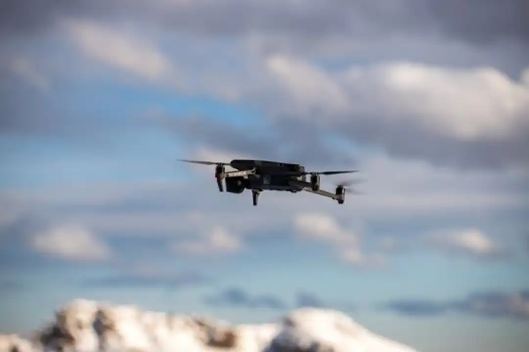 Drone terbang di atas pegunungan bersalju dengan awan dramatis