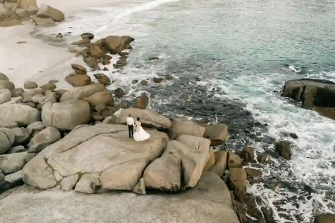Pasangan pengantin di pantai berbatu dekat laut, momen romantis.