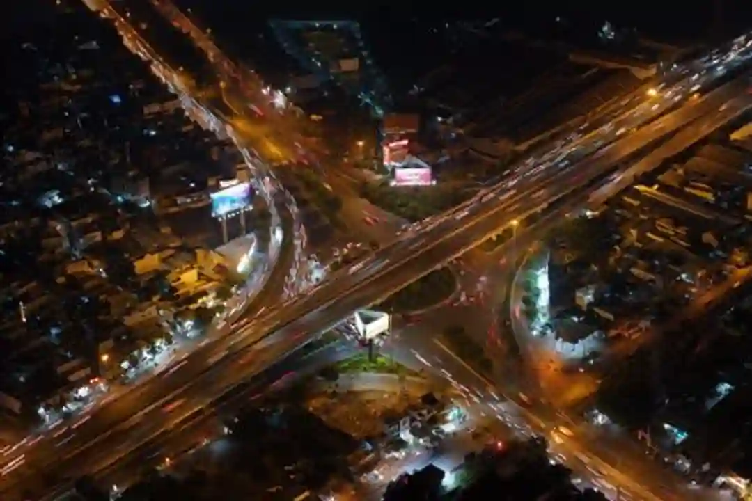 Aliran lalu lintas malam hari yang ramai di persimpangan kota besar, dilihat dari udara.
