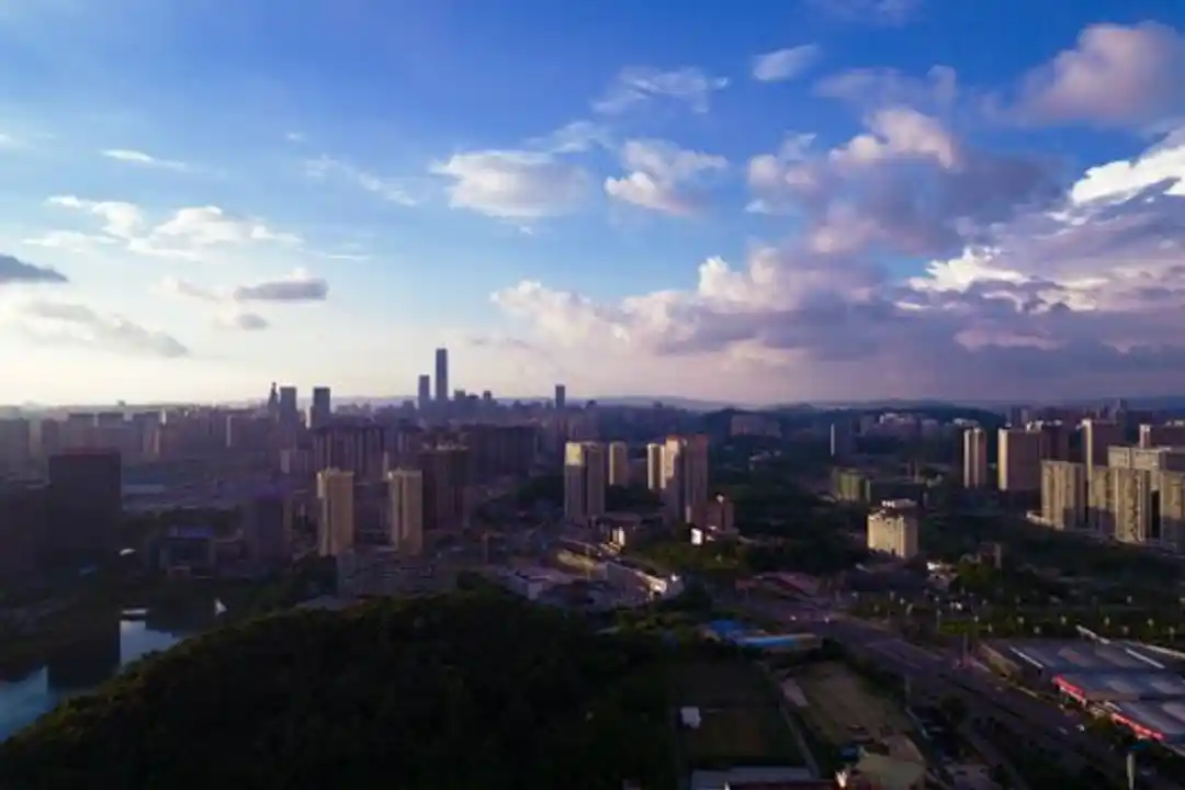 Pemandangan kota modern yang menakjubkan dari udara saat senja, dengan gedung pencakar langit dan awan berwarna-warni.