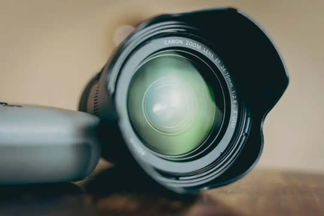 Lensa kamera close-up di atas meja kayu, ideal untuk tema pelatihan fotografi dan peralatan.