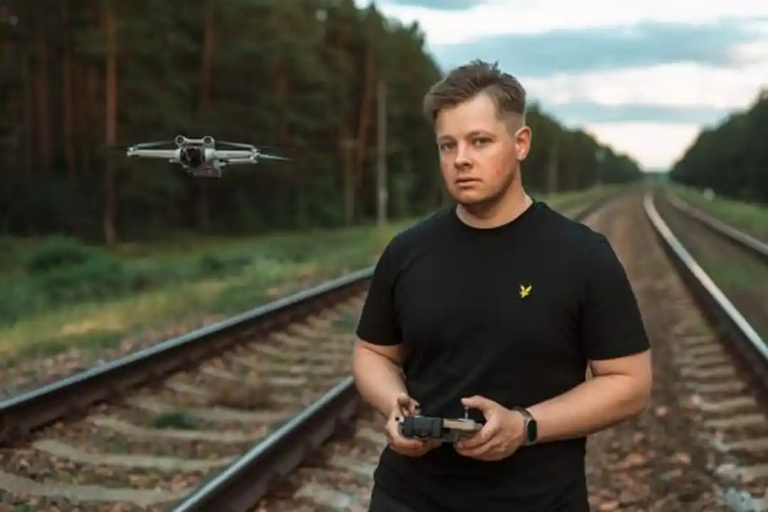 Pelatihan sertifikasi pilot drone: Pria mengendalikan drone di jalur kereta api dalam hutan pedesaan. Teknologi bertemu alam.