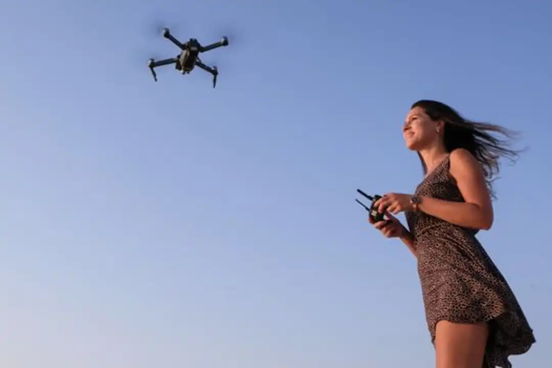 Wanita menikmati menerbangkan drone di luar ruangan di bawah langit biru cerah untuk pelatihan sertifikasi pilot drone.